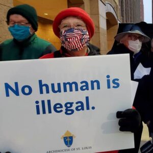 Sister Sean holding a sign reading "No human is illegal"