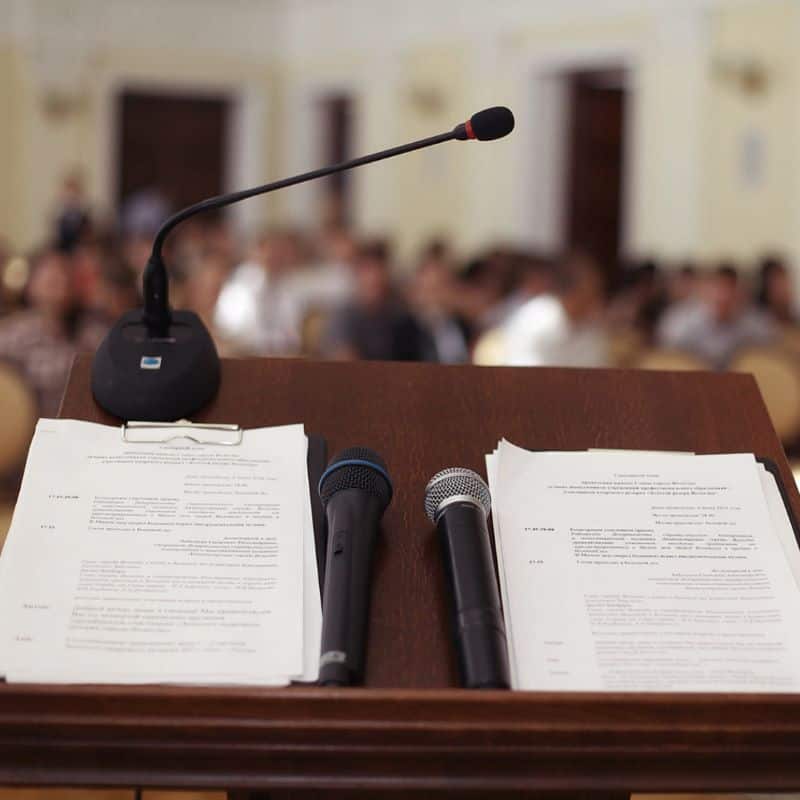 Looking out to a crowd over a podium with microphones 