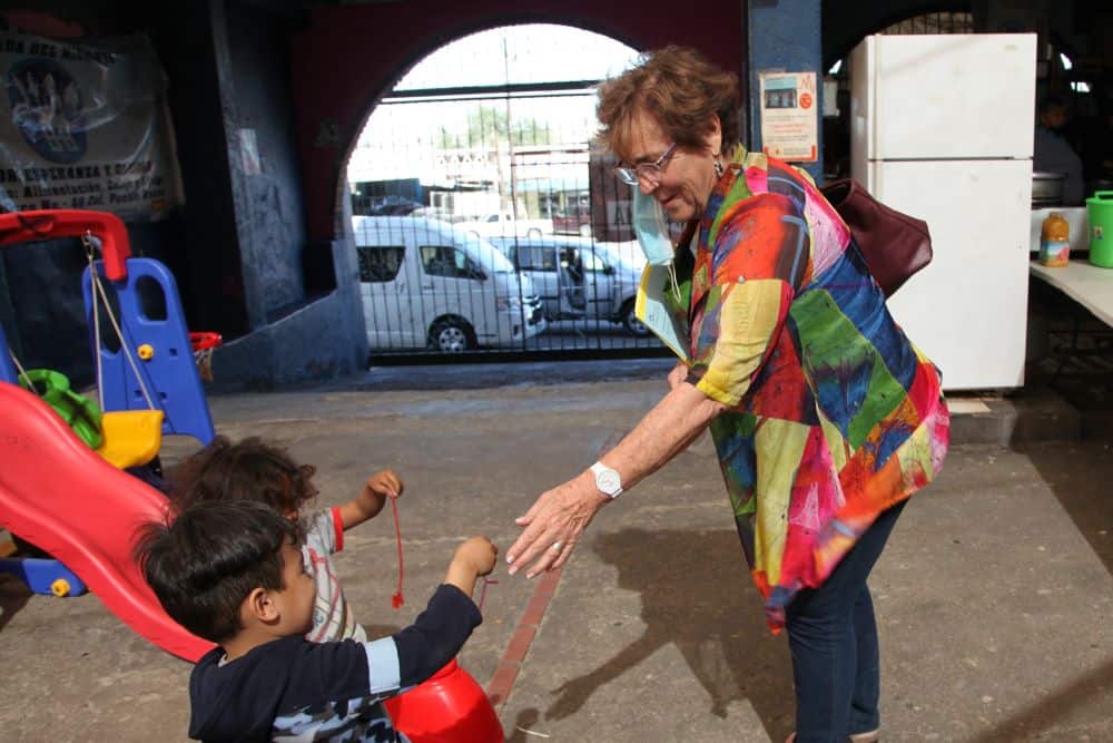 A sister reaches out to two migrant children near a playground