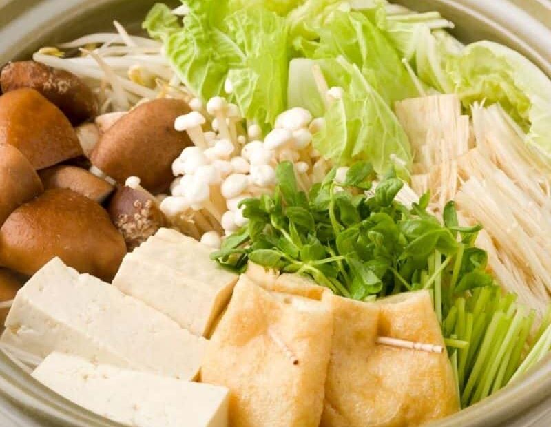 A Japanese hot pot containing mushrooms, tofu, sprouts and other vegetables
