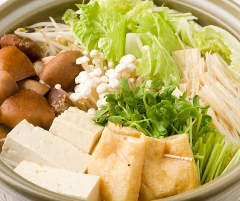 A Japanese hot pot containing mushrooms, tofu, sprouts and other vegetables