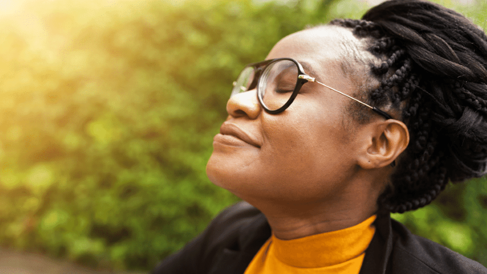 A woman takes a deep breath with a content look on her face