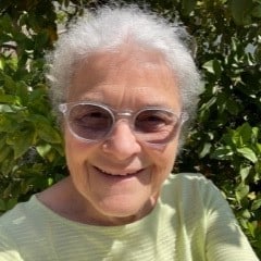 Photo of Sister Roseanne Belpedio. She is wearing a yellow shirt and the background is greenery. 