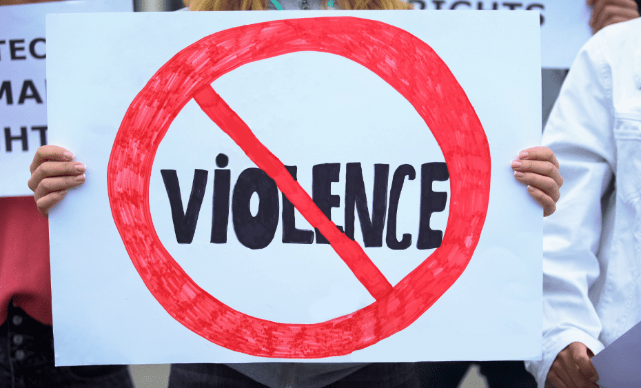 Someone at a rally holds up a sign with the word "violence" in a red circle with a strikeout line through it