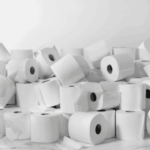 A haphazard pile of dozens of toilet paper roles sit in front of a white backdrop