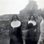 An old black and white photo shows four sisters wearing habits speaking a child and a woman. A mess of tsunami rubble extends to the horizon.