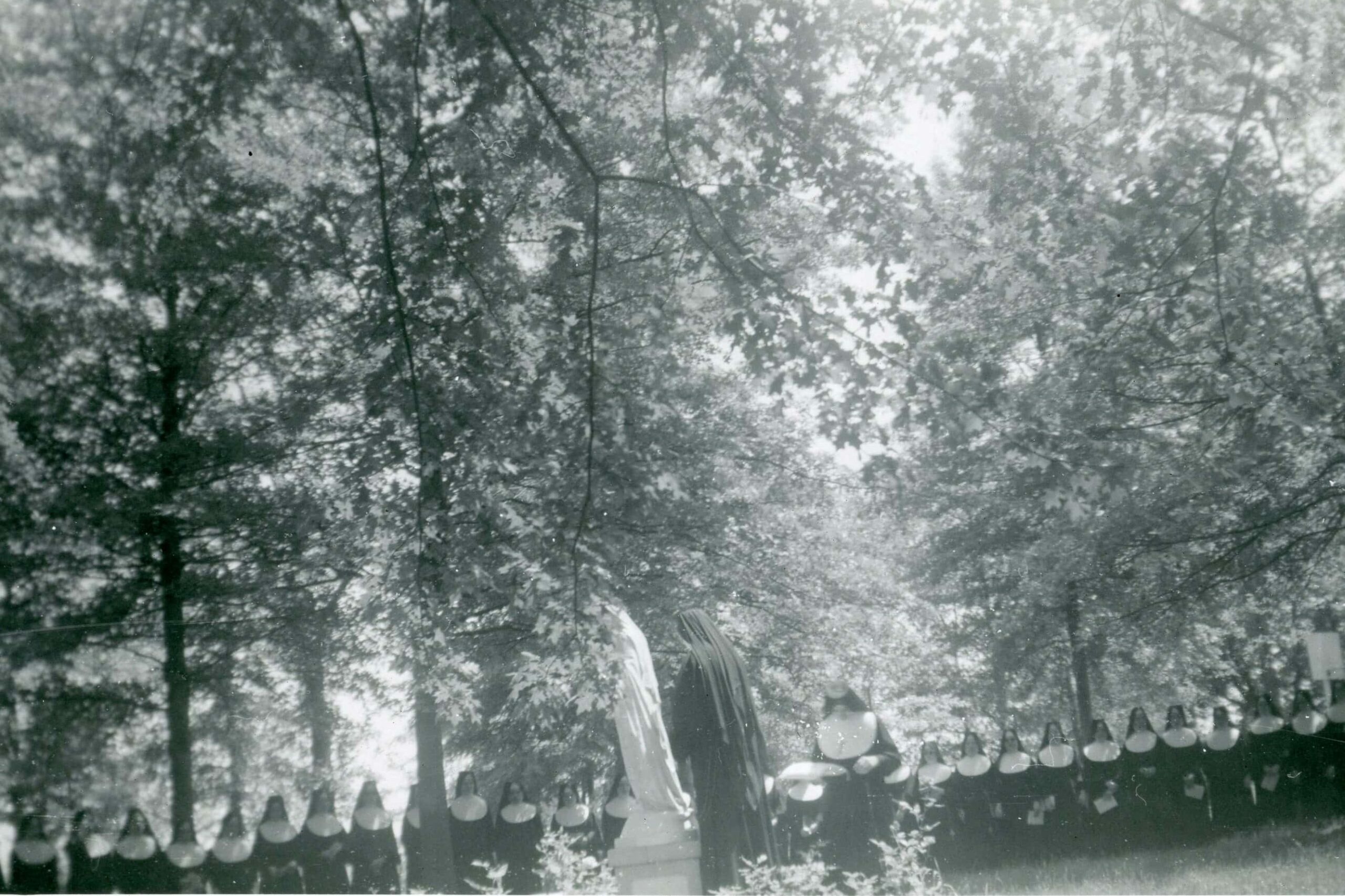 Black and white photo of sisters and novices of the Sisters of St. Joseph of Carondelet placing a flower wreath on a statue of Mary.