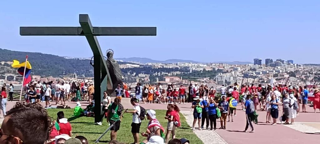 World Youth Day 2023 pilgrims congregating around a statue of the crucifix.