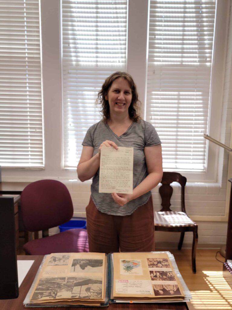 Archivist Sally Budge holding a prisoner of war letter from the archives.