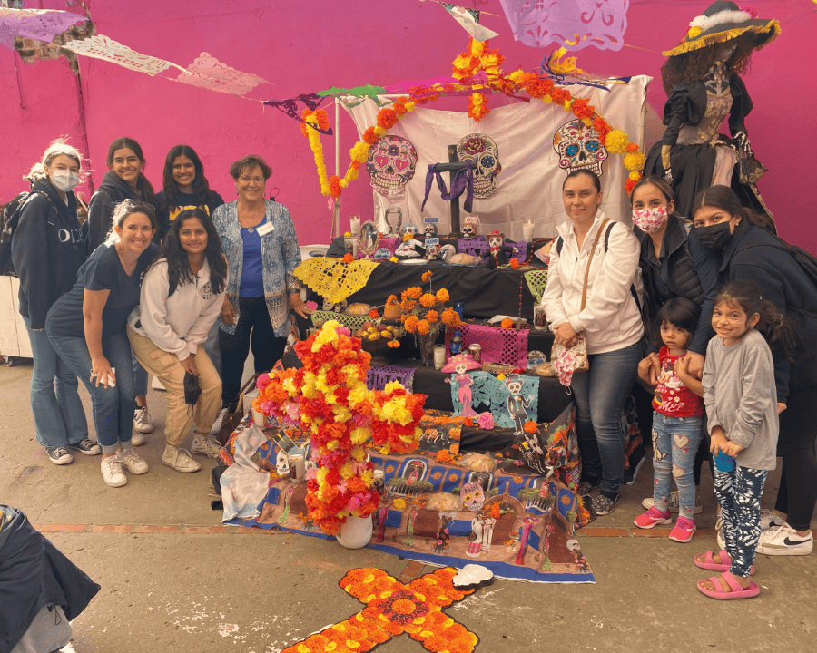 Group stands next to a Día de los Muertos altar.