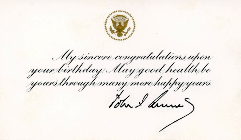 A scan of a card with the U.S. Presidential Seal embossed in gold at the top reads "My sincere congratulations upon your birthday. May good health be yours through many more happy years." with John F. Kennedy's signature 