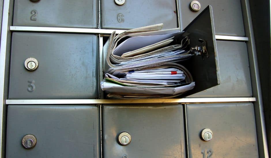 A locked mailbox is stuffed full of mail so that it cannot be closed