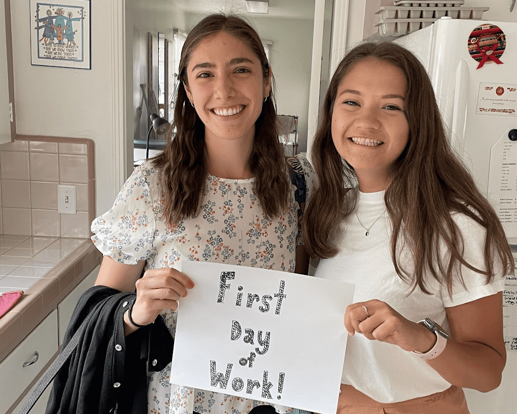 SJWs Suzanne Scanameo and Elaina Wall holding a "First Day at Work" sign.