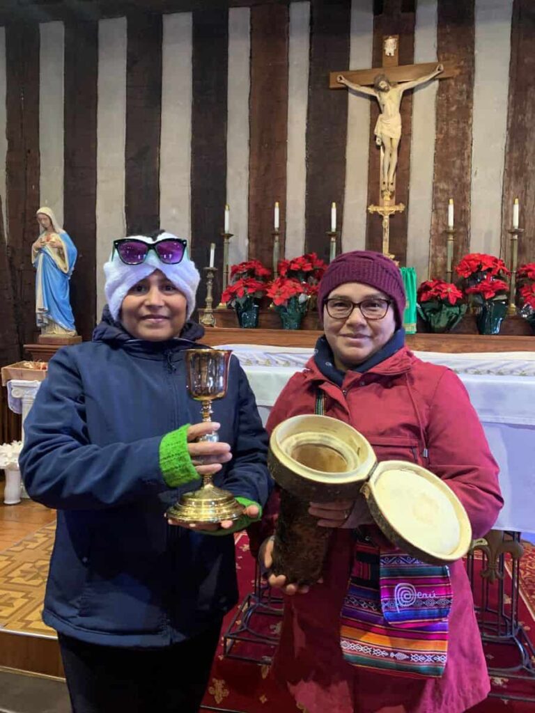 Two sisters holding the chalice from the Holy Family Log Church and its deerskin container
