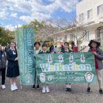 A group of three students and two teachers hold up large green banners reading "Saint Joseph" and "Walkathon"