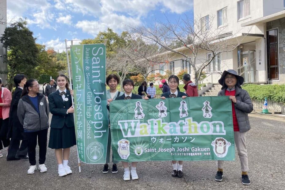 A group of three students and two teachers hold up large green banners reading "Saint Joseph" and "Walkathon"