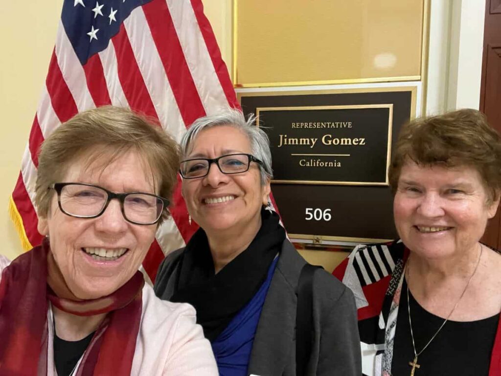 Three women stand in front of the office of a congressmember