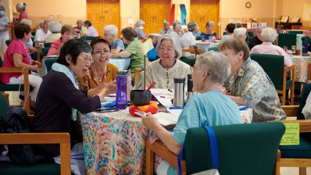 Two Japanese sisters, with their interpreter between them, engage in animated discussion at a round table with two other sisters.