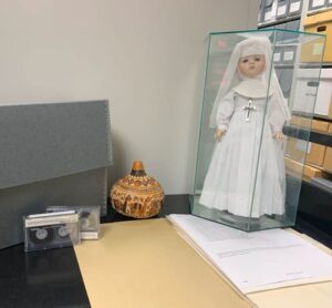 Audio tapes, a nun doll, files, and decorated pottery displayed in the archives