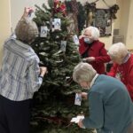 Four sisters hanging prayer ornaments on a tree