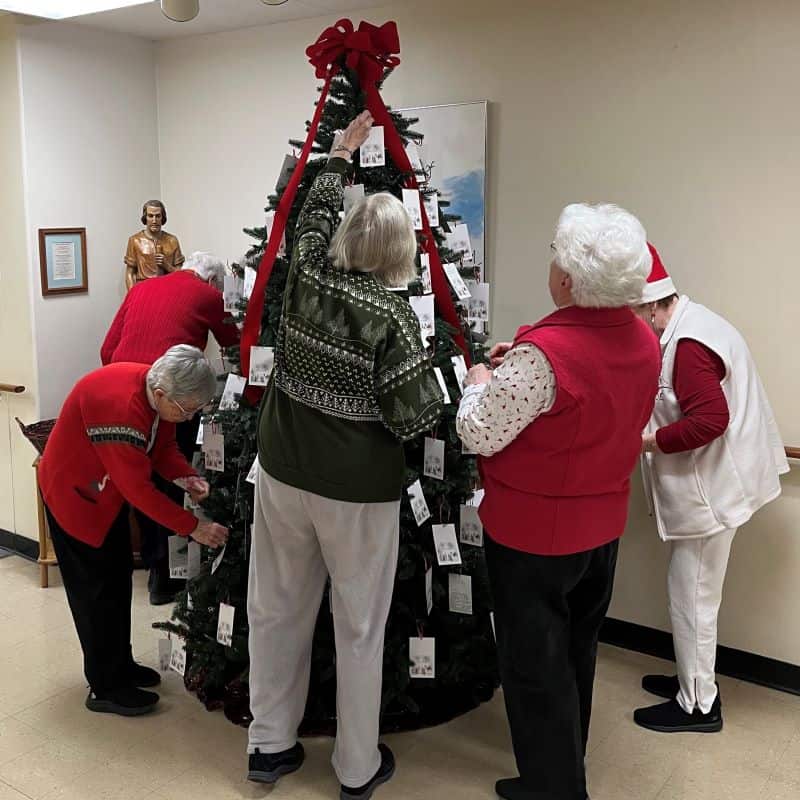 Sisters Margie Vincent, Alma Jones, Danielle Bonetti, Maura Simms, Ranah Phelan and Peggy Parnell decorating a Christmas tree