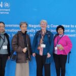 Four sisters stand together in front of a wall-to-wall sign for the UN negotiating session