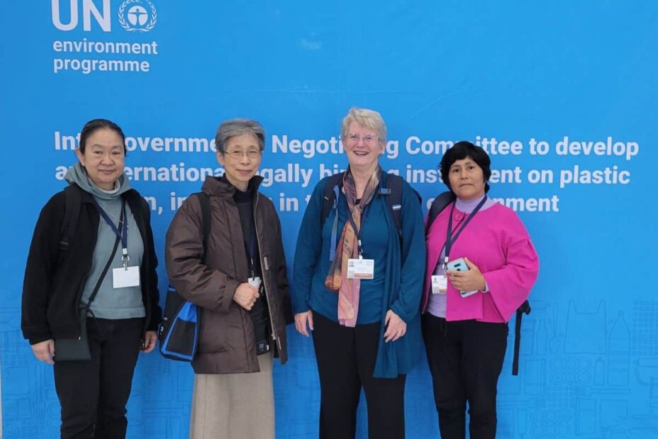 Four sisters stand together in front of a wall-to-wall sign for the UN negotiating session