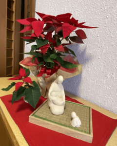 Japanese-style statue of the Virgin and Child in front of a poinsettia