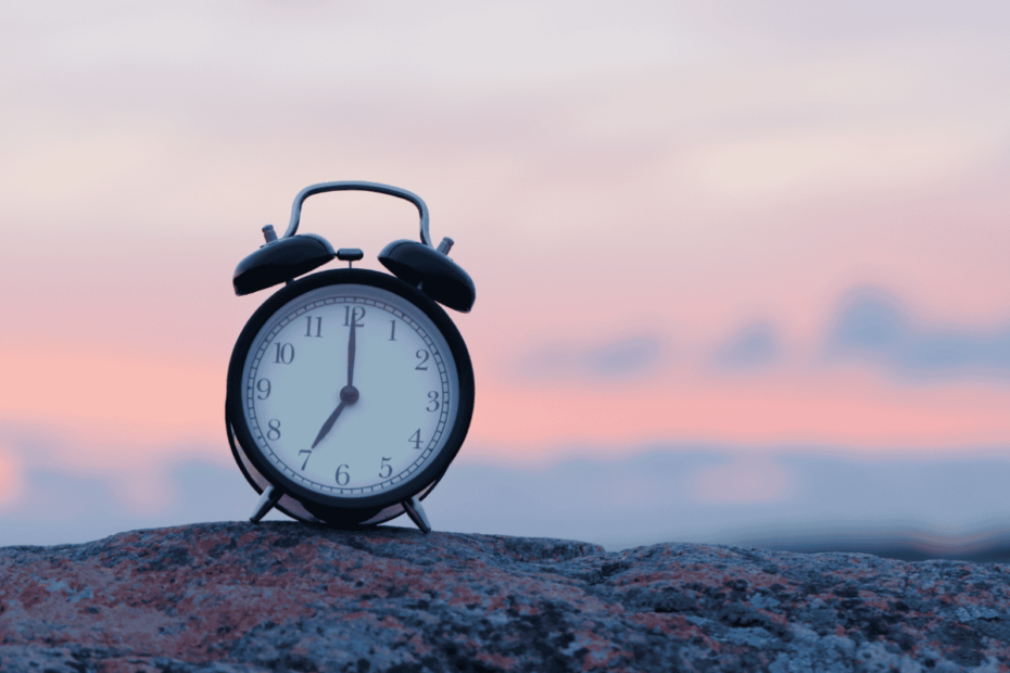 Photo of an alarm clock on a rock at sunrise