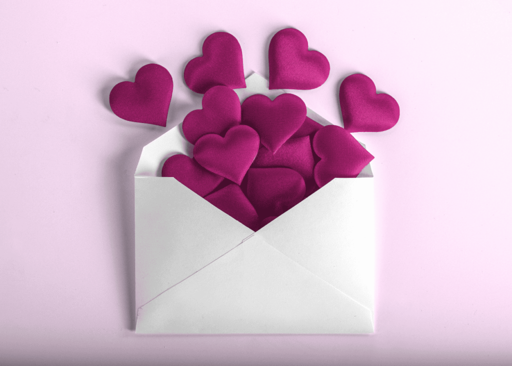 Photo of a white envelope with magenta hearts piled inside