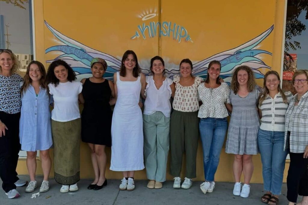 St. Joseph Workers pose for a group photo in front of a painting of wings