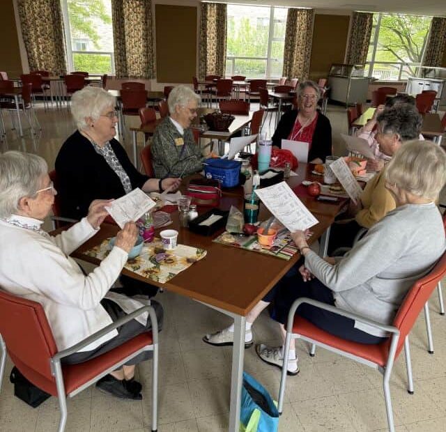 Seven women gathered around a table sharing a meal and preparing raffle tickets