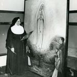 A black and white photo of Sister Evelyn Marie Reznick, CSJ next to her painting, "Our Lady of Fatima"