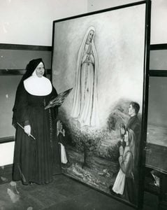 A black and white photo of Sister Evelyn Marie Reznick, CSJ next to her painting, "Our Lady of Fatima"